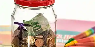 צנצנת חיסכון עם מטבעות ושטרות - ניהול התקציב המשפחתי
